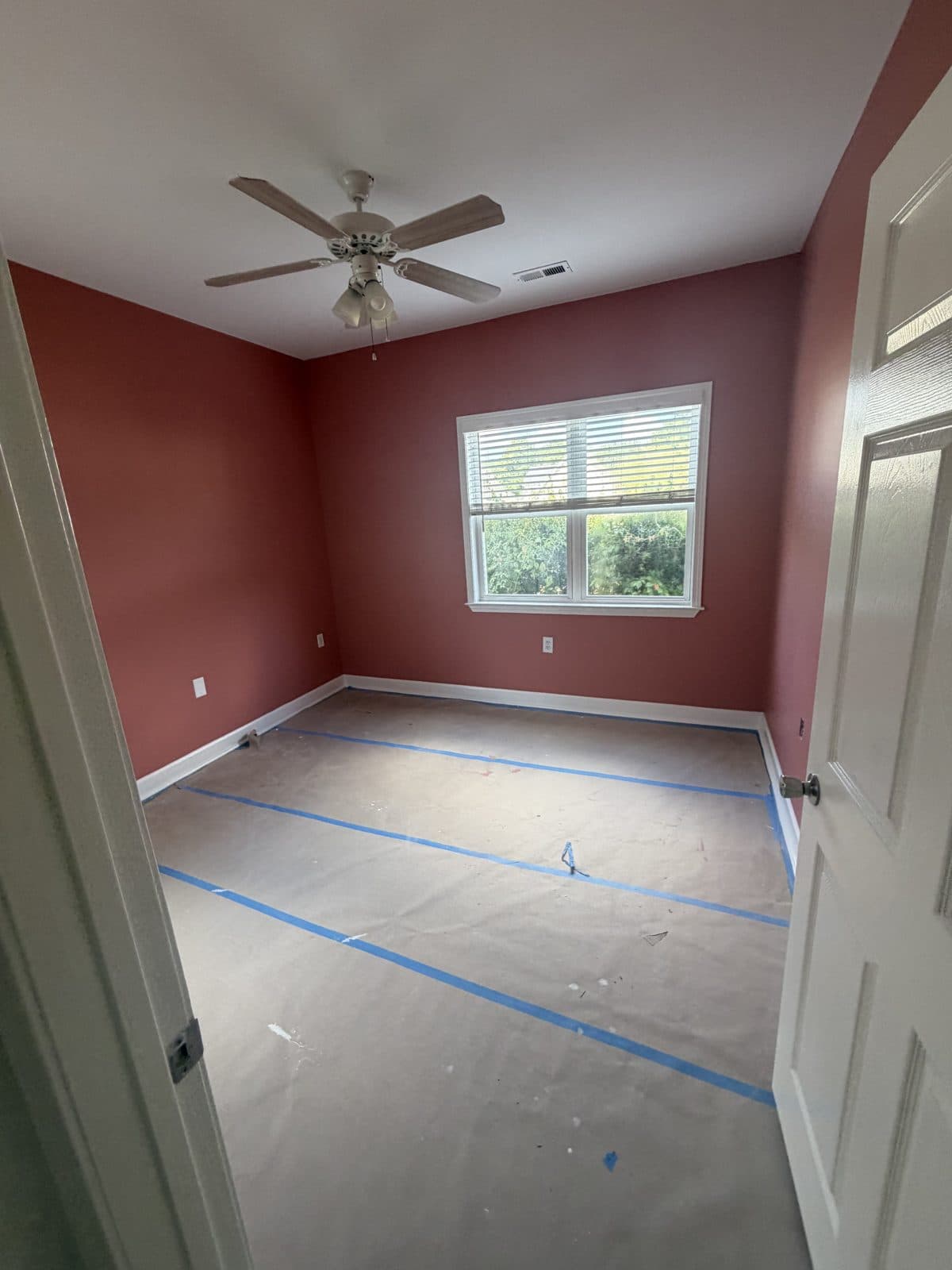 Rose-red bedroom with the entire floor papered and the seams taped before painting
