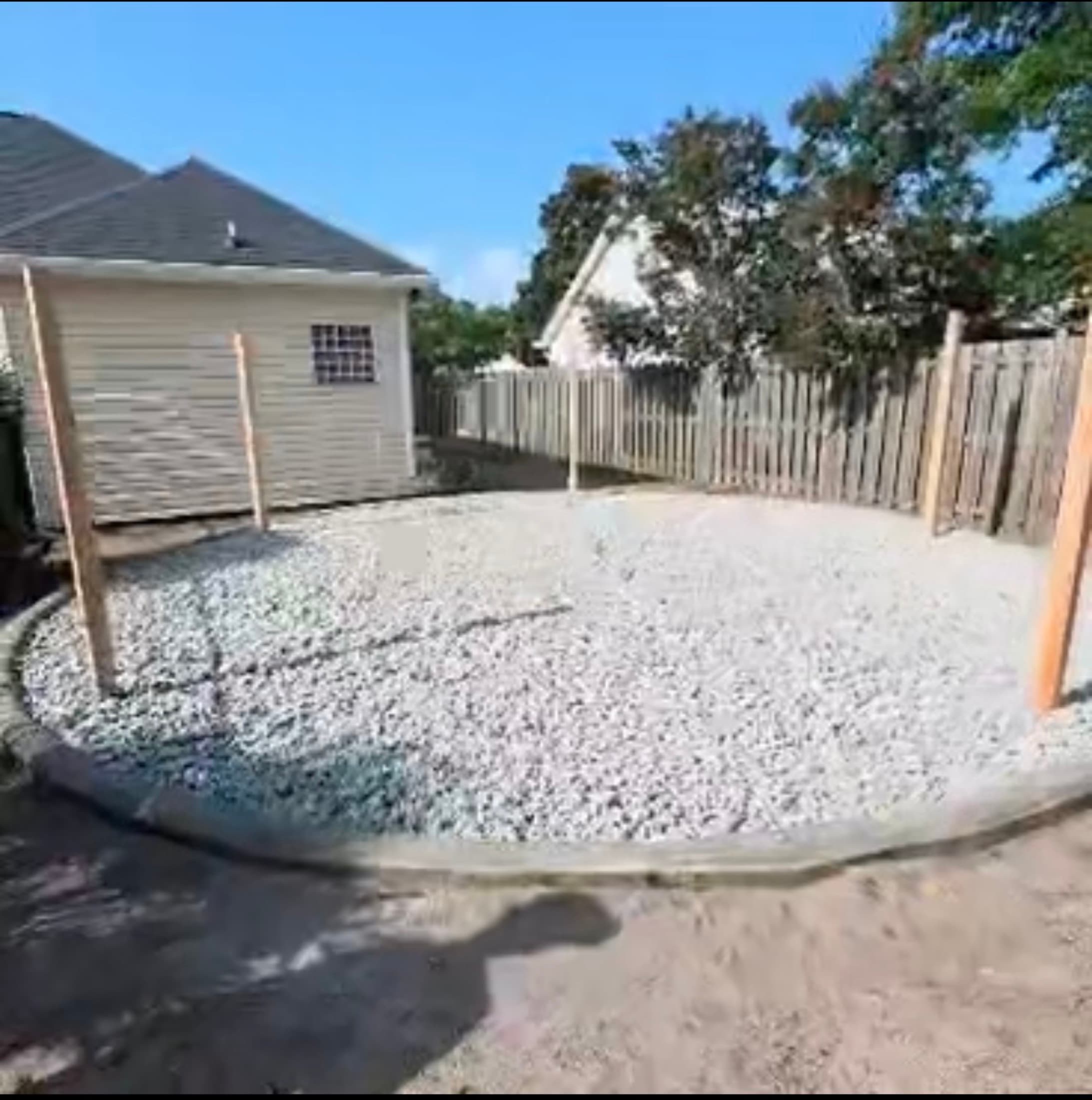 Curved concrete border filled with white stone base, with timber posts set for a structure