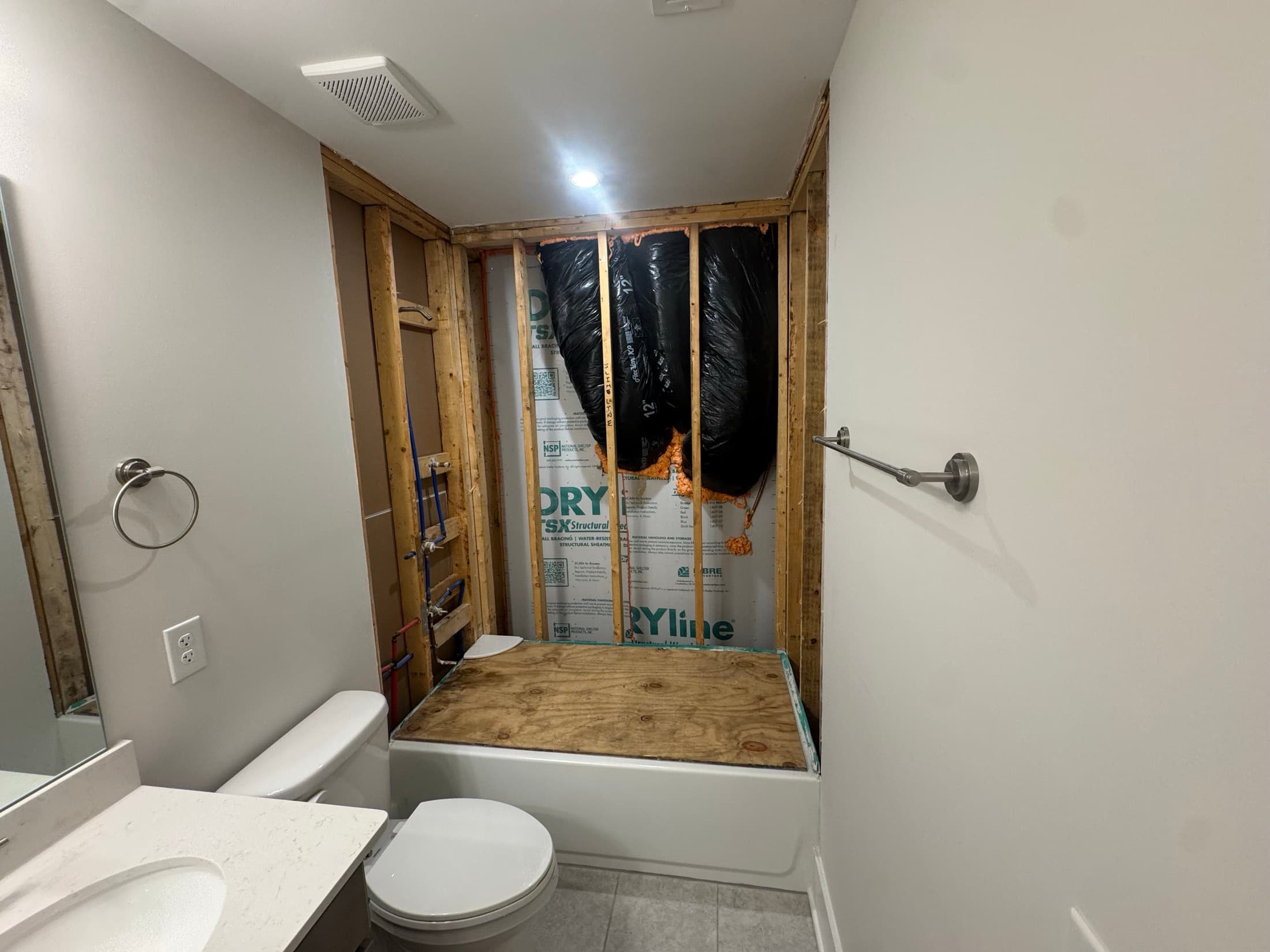 Shower alcove stripped to the studs with sheathing and plywood exposed
