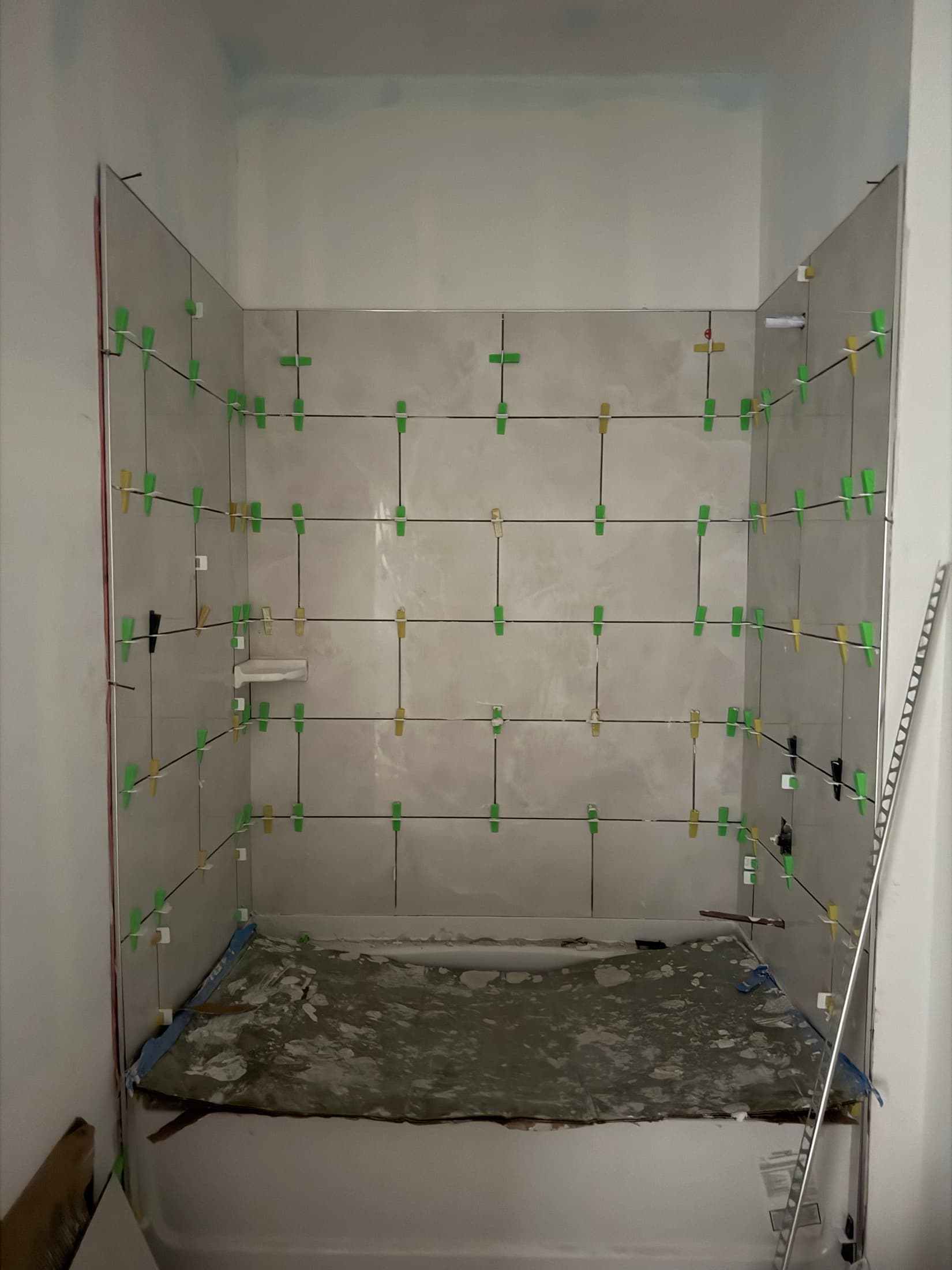 Tile set with leveling clips still in place across the surround